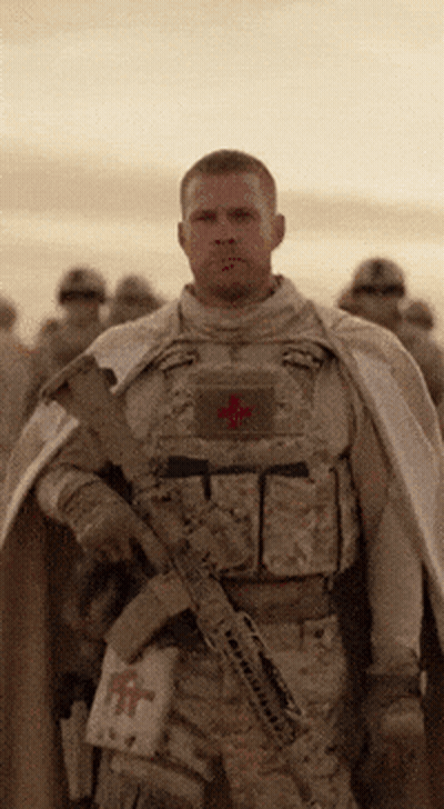 A Soldier With A Red Cross On His Chest Is Holding A Gun GIF