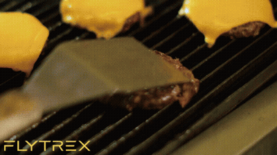 A Spatula Is Being Used To Turn A Hamburger On A Grill With Flytrex Written In The Upper Right Corner GIF
