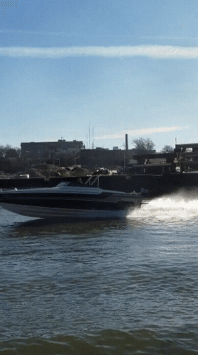 A Speed Boat Is Going Through The Water With A City In The Background GIF