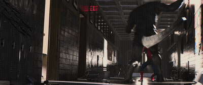 A Spider Man Is Standing In A Hallway With A Red Exit Sign GIF