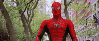A Spider Man Is Standing In Front Of Trees And Buildings GIF
