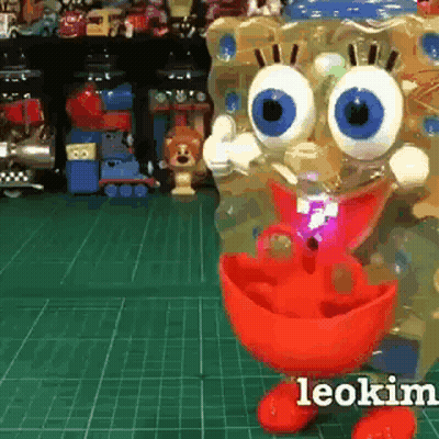 A Spongebob Doll Is Standing On A Green Cutting Board . GIF