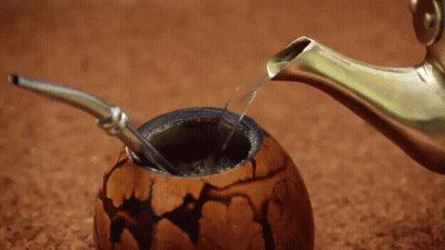 A Spoon Is Being Used To Pour Liquid Into A Bowl GIF