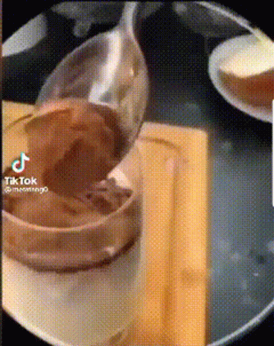 A Spoon Is Sitting On A Plate Next To A Bowl Of Food . GIF