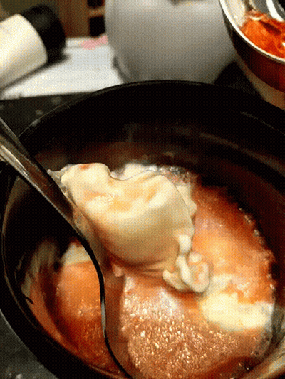 A Spoon Is Stirring A Sauce In A Pot GIF