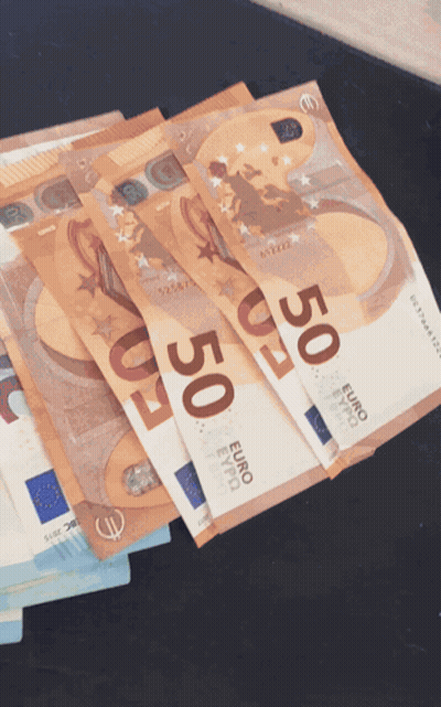 A Stack Of 50 Euro Bills On A Black Surface GIF