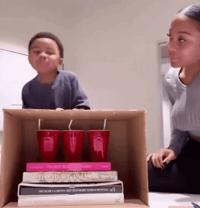 A Stack Of Books Including Oscar De La Renta 'S Legendary World Of Style Sit On A Cardboard Box GIF