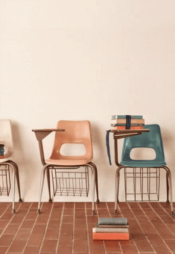 A Stack Of Books Sits On A Brick Floor In Front Of A Wall That Says " Ed " GIF