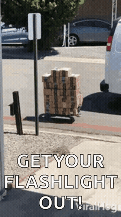 A Stack Of Boxes On A Cart On The Side Of The Road With The Words `` Get Your Flashlight Out '' . GIF