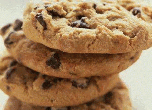 A Stack Of Chocolate Chip Cookies Sitting On Top Of Each Other On A White Plate . GIF