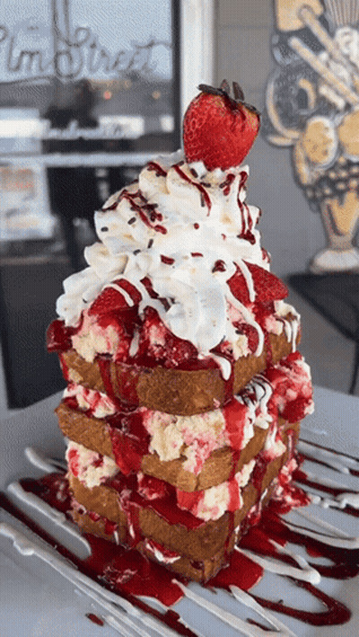 A Stack Of French Toast With Strawberries Whipped Cream And Sauce GIF