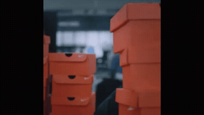 A Stack Of Orange Nike Boxes In A Dark Room GIF
