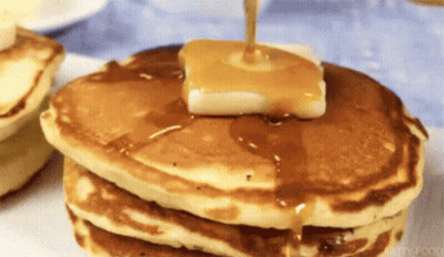 A Stack Of Pancakes With Butter And Syrup Being Poured On Top . GIF
