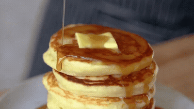 A Stack Of Pancakes With Butter And Syrup Being Poured On Top GIF