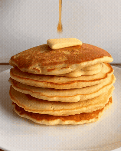 A Stack Of Pancakes With Syrup And Butter Being Poured On Top GIF