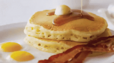 A Stack Of Pancakes With Syrup Being Poured On Them GIF
