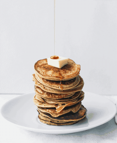A Stack Of Pancakes With Syrup Being Poured On Top Of Them GIF