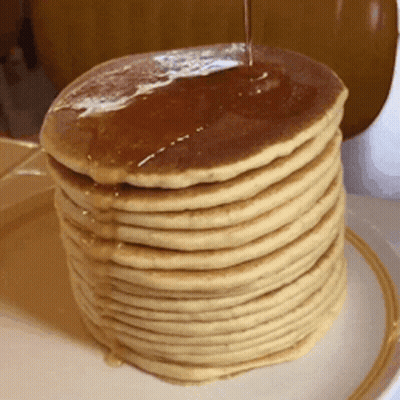 A Stack Of Pancakes With Syrup Being Poured On Top Of Them GIF