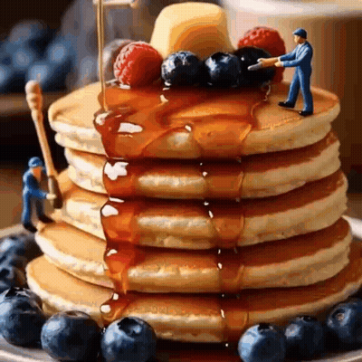 A Stack Of Pancakes With Syrup , Blueberries , Raspberries , And Butter . GIF