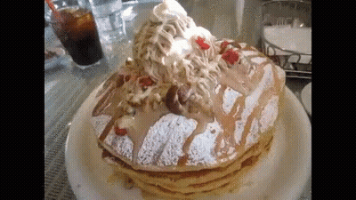 A Stack Of Pancakes With Whipped Cream And Strawberries On Top On A Plate . GIF