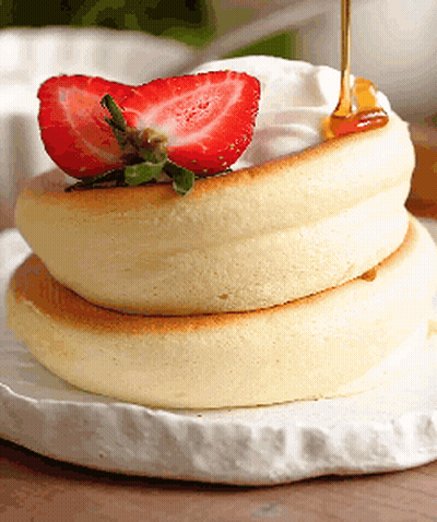 A Stack Of Pancakes With Whipped Cream And Strawberries GIF