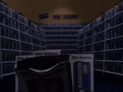 A Stack Of Vhs Tapes In A Library With A Book That Says Buster Video GIF