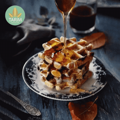 A Stack Of Waffles On A Plate With Syrup Being Poured Over Them With A Tarim Logo In The Background GIF