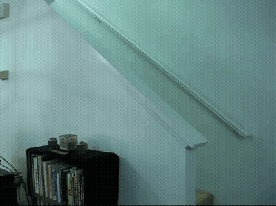 A Staircase With A Bookshelf Underneath It And A White Railing GIF