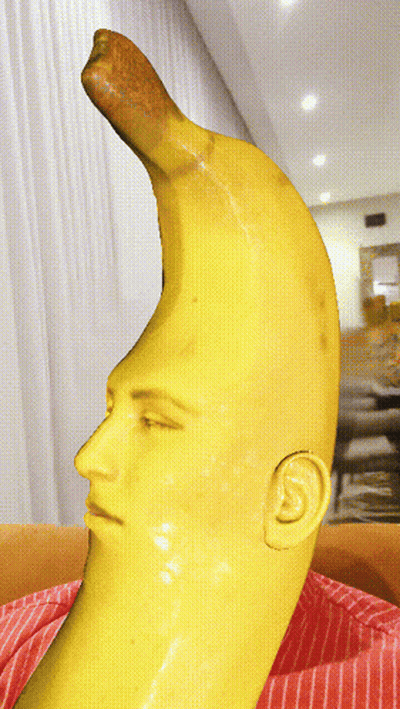 A Statue Of A Banana With A Face And Ear On It GIF