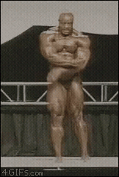 A Statue Of A Bodybuilder Is Standing On A Stage With His Arms Crossed GIF