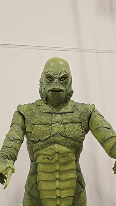 A Statue Of A Creature Has Signatures On It Including Those Of John Carpenter And Peter Fonda GIF