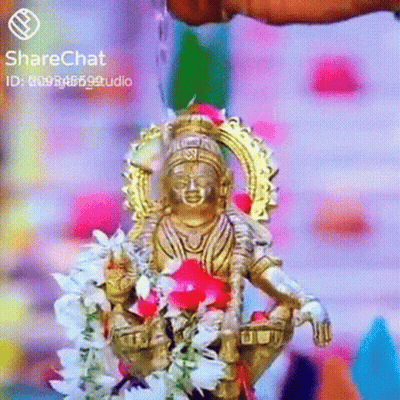 A Statue Of A Deity Is Surrounded By Flowers And Water Being Poured On It . GIF