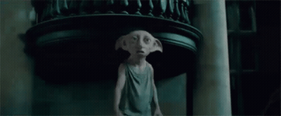 A Statue Of A Dobby From Harry Potter Is Standing In A Dark Room Holding A Cat . GIF