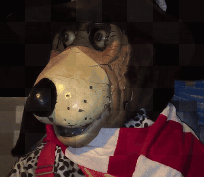A Statue Of A Dog Wearing A Cowboy Hat And A Scarf GIF