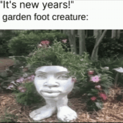 A Statue Of A Garden Foot Creature With Flowers On Its Head GIF