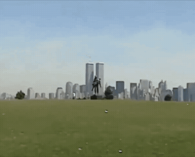 A Statue Of A Man Carrying Another Man In Front Of The Twin Towers Of The World Trade Center GIF