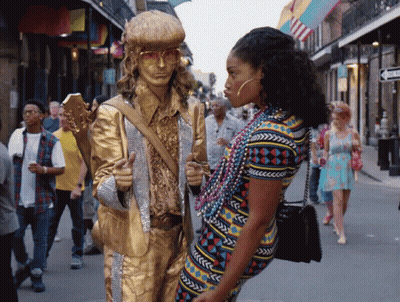 A Statue Of A Man Holding A Guitar Is Standing Next To A Woman Wearing Beads GIF