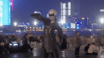 A Statue Of A Man In A Black Suit Is Standing In Front Of A City Skyline At Night GIF