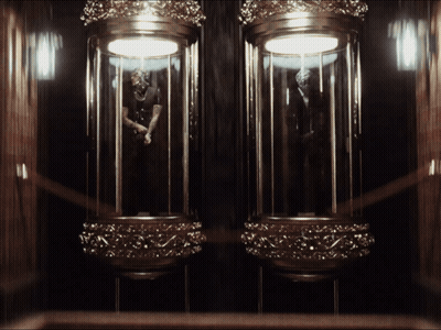 A Statue Of A Man In A Suit Is Displayed In A Glass Case GIF