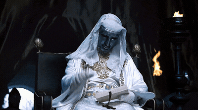 A Statue Of A Man In A White Robe Is Reading A Book GIF