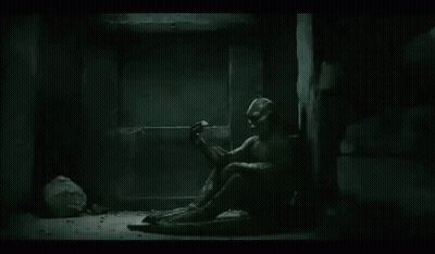 A Statue Of A Man Is Sitting On The Floor In A Dark Room . GIF