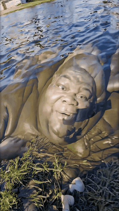 A Statue Of A Man Laying In The Water GIF