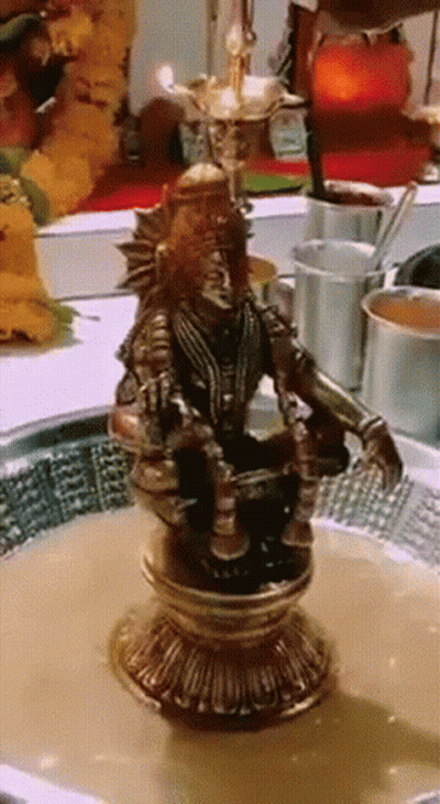 A Statue Of A Man Sitting On A Pedestal With A Bowl Of Liquid In Front Of Him GIF