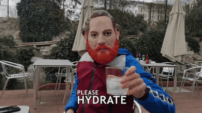 A Statue Of A Man With A Red Beard Is Holding A Glass Of Water With The Words Please Hydrate Above Him GIF