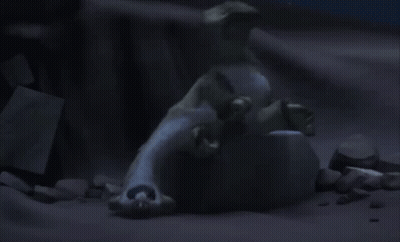 A Statue Of A Polar Bear Laying On Top Of A Rock In The Dark . GIF