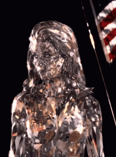 A Statue Of A Woman Made Of Crystals Is Standing In Front Of An American Flag GIF