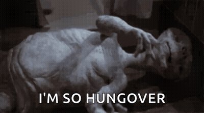 A Statue Of An Alien Is Laying On The Floor With The Words `` I 'M So Hungover '' Written On The Bottom . GIF