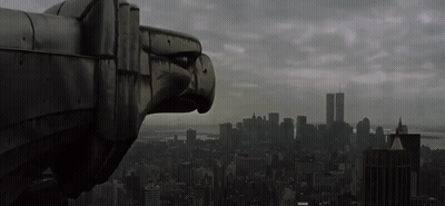 A Statue Of An Eagle Looks Out Over A City With The Twin Towers In The Background GIF