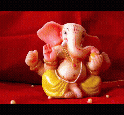 A Statue Of Ganesha Is Sitting On A Red Surface With Pearls Around It GIF