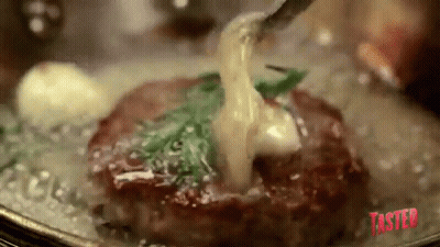 A Steak Is Being Cooked In A Pan With A Fork And Sauce Being Poured Over It . GIF